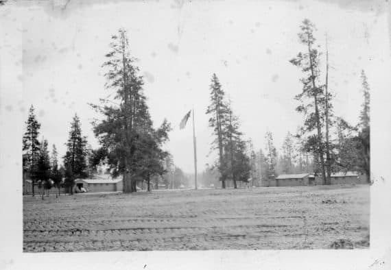 A historic photo of Camp Abbot, circa 1943, featuring barracks and an American flag. A historic photo of Camp Abbot, circa 1943, featuring barracks and an American flag.