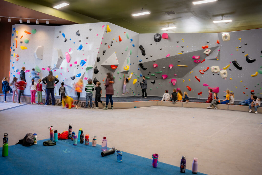 Kids climbing on rock climbing wall with colorful mounts.