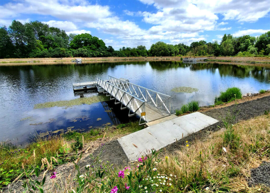 Accessible ramp on pond with bright green foliage nearby.