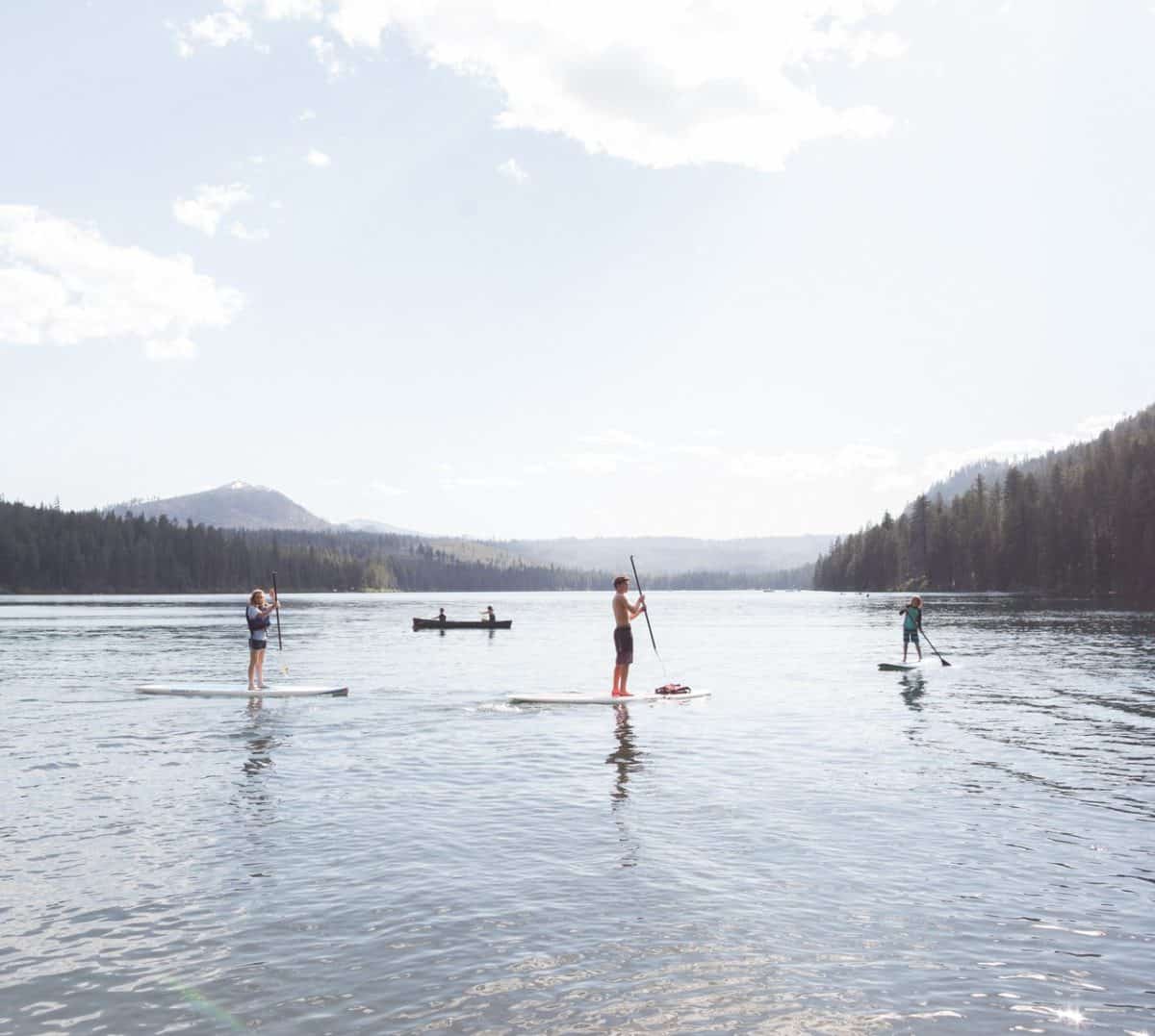 Three paddleboarders join a canoe on the water of Elk Lake near Bend, Oregon. Three paddleboarders join a canoe on the water of Elk Lake near Bend, Oregon.
