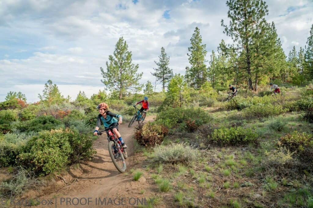 A group of bikers ride down a trail. 