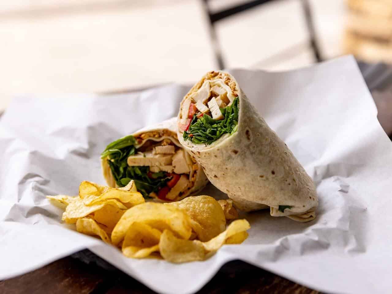 A wrap and chips in a basket. A wrap and chips in a basket.