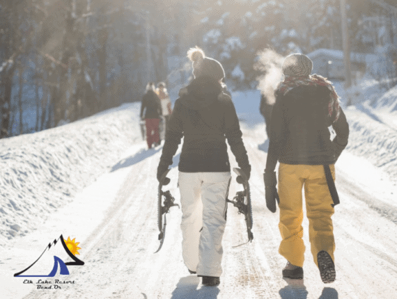 A pair of friends walk along a snow-covered road while holding snowshoes at Elk Lake near Bend, Oregon. A pair of friends walk along a snow-covered road while holding snowshoes at Elk Lake near Bend, Oregon.