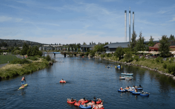 People float in tubes and on paddleboards on the Deschutes River through the Old Mill District in Bend, Oregon. People float in tubes and on paddleboards on the Deschutes River through the Old Mill District in Bend, Oregon.